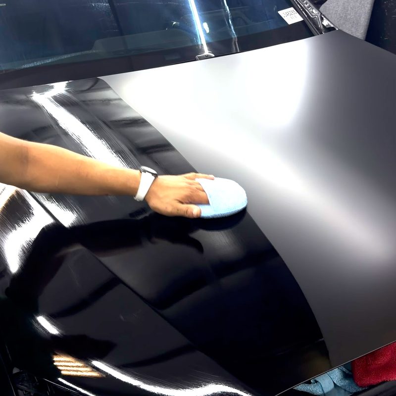 Coating being worked into black paint with an applicator pad