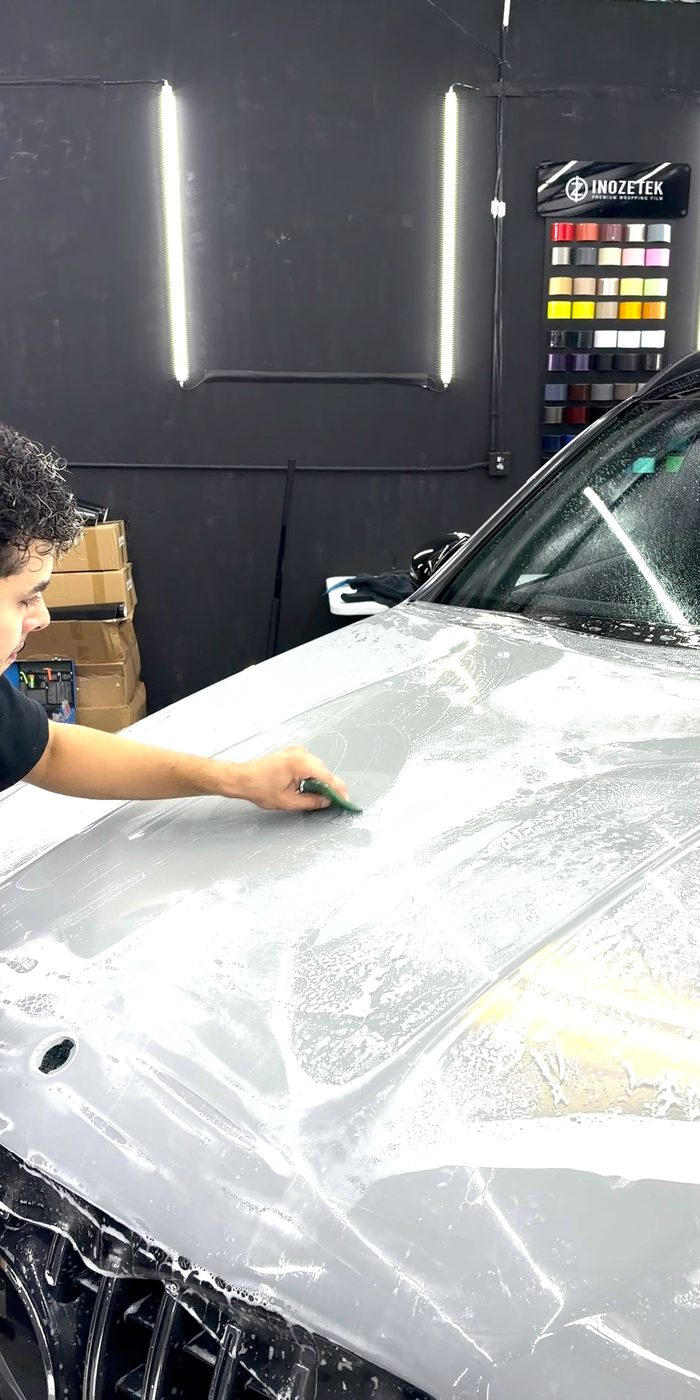 Installer squeegeeing paint protection film onto a hood